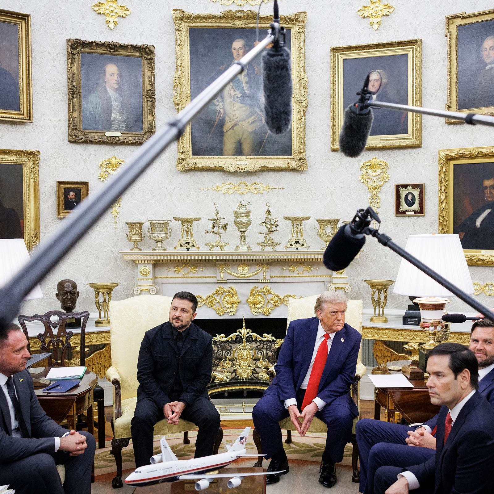 President Donald Trump and Ukraine President Volodymyr Zelensky sit on chairs in the oval office. They are surrounded by...